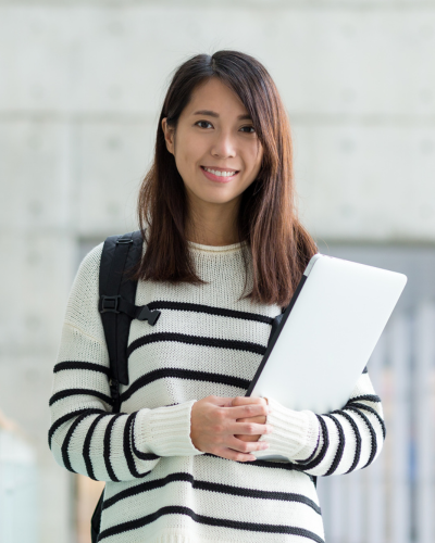 A young asian woman in a black and white striped knitted sweater can be seen. She has brown hair and is holding a laptop.